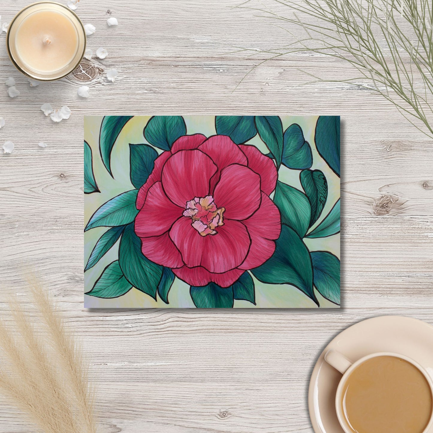 Floral artwork on a wooden surface with a cup of coffee and candle.
