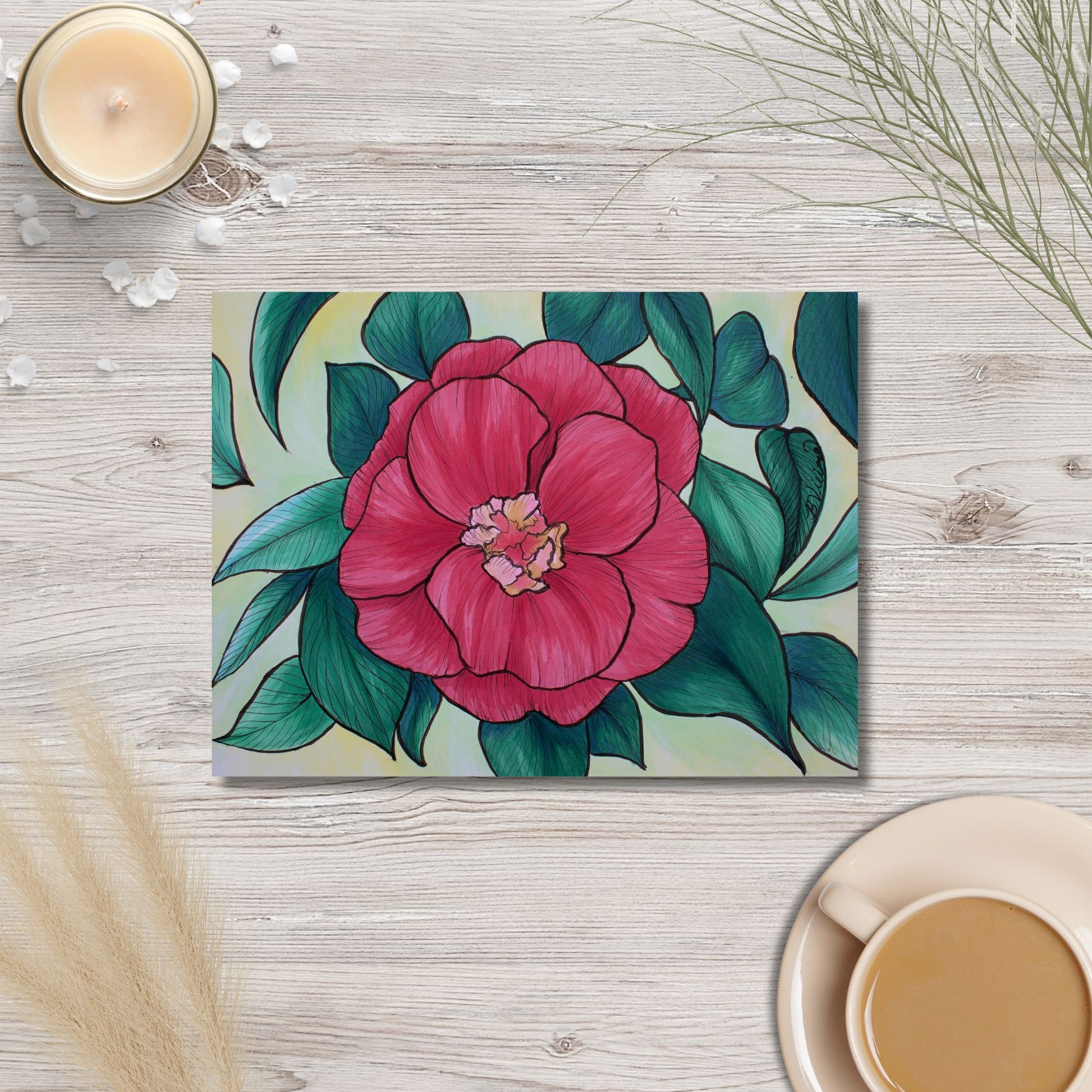 Floral artwork on a wooden surface with a cup of coffee and candle.