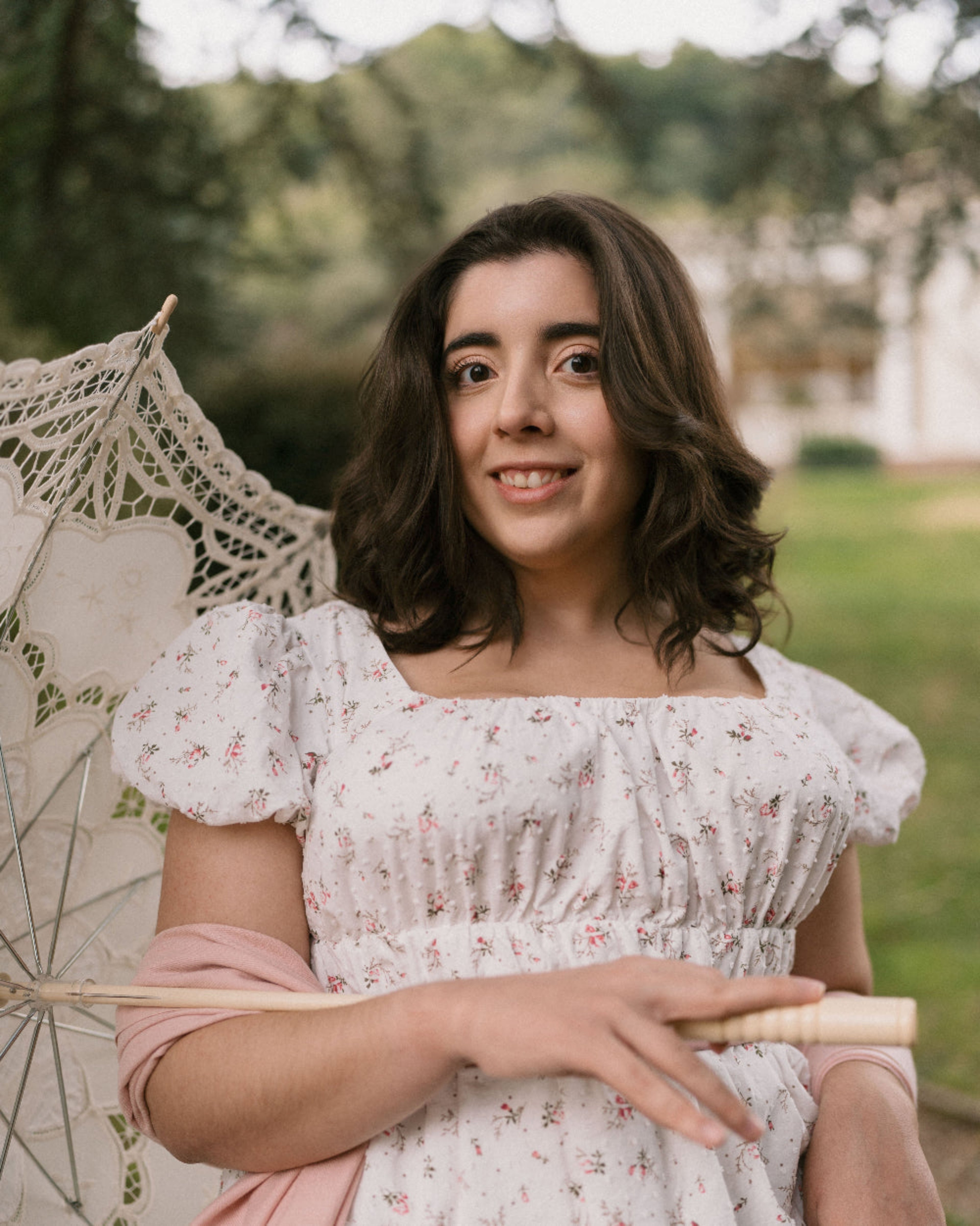 Woman in a floral dress holding a lace parasol outdoors