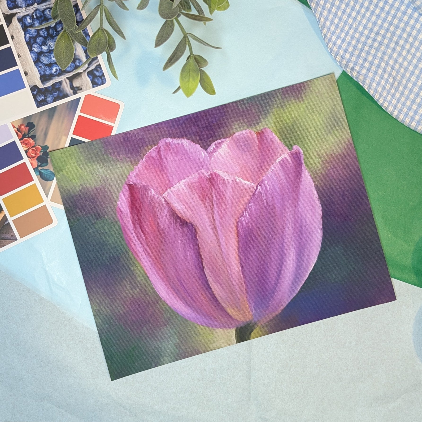 Painting of a pink tulip on a textured surface with color swatches and plants.