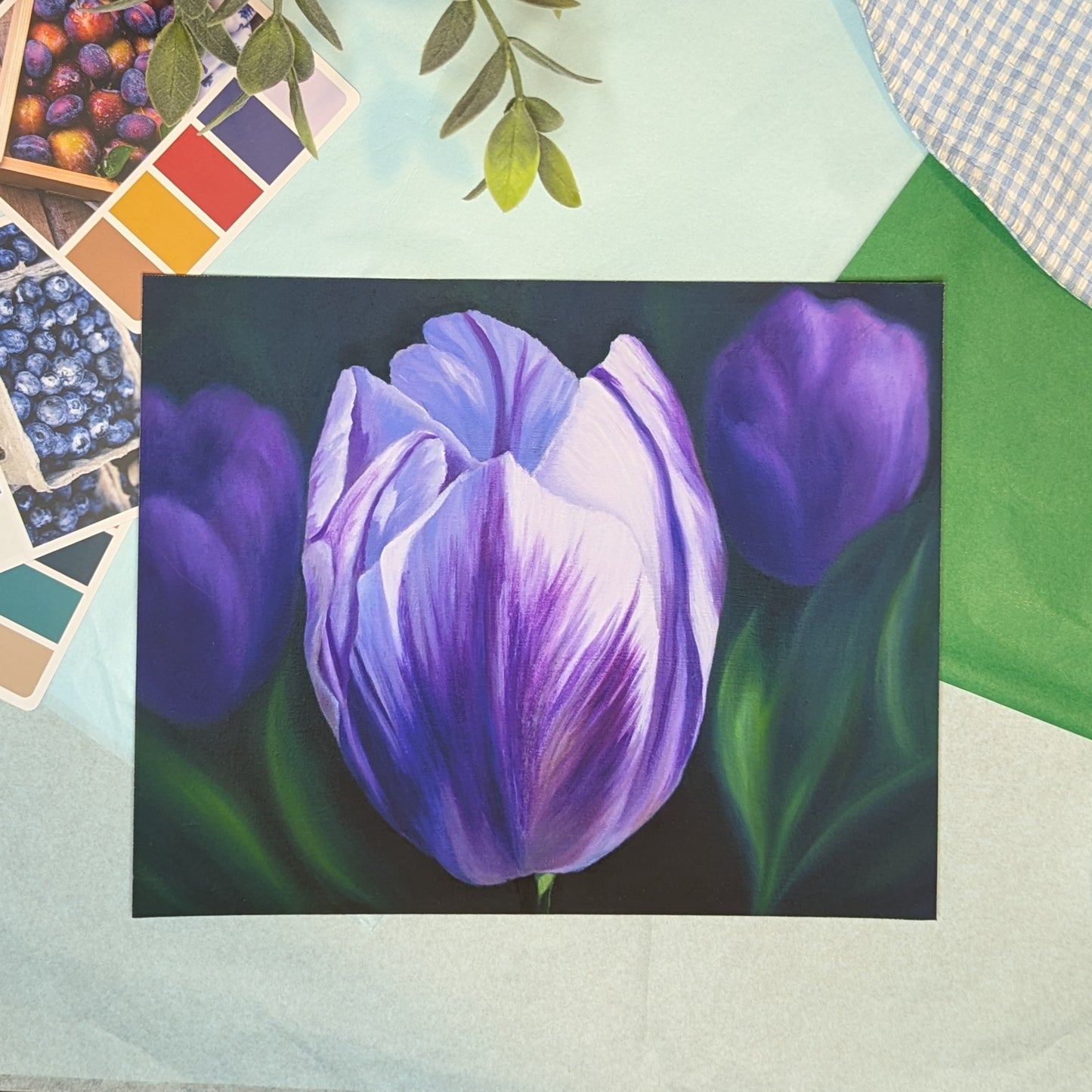 Painting print of purple tulips on a textured surface with color swatches and leaves.