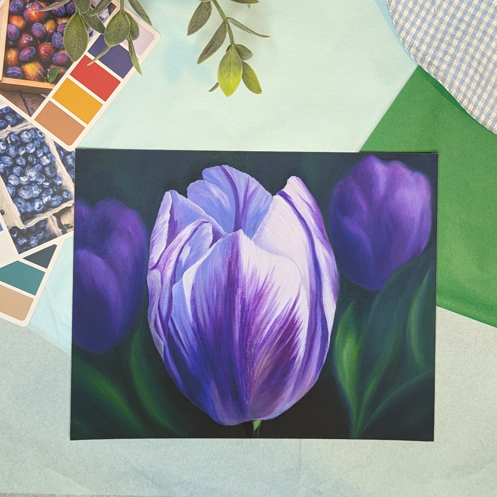 print of a painting of a purple tulip on a colorful background with color swatches and leaves.