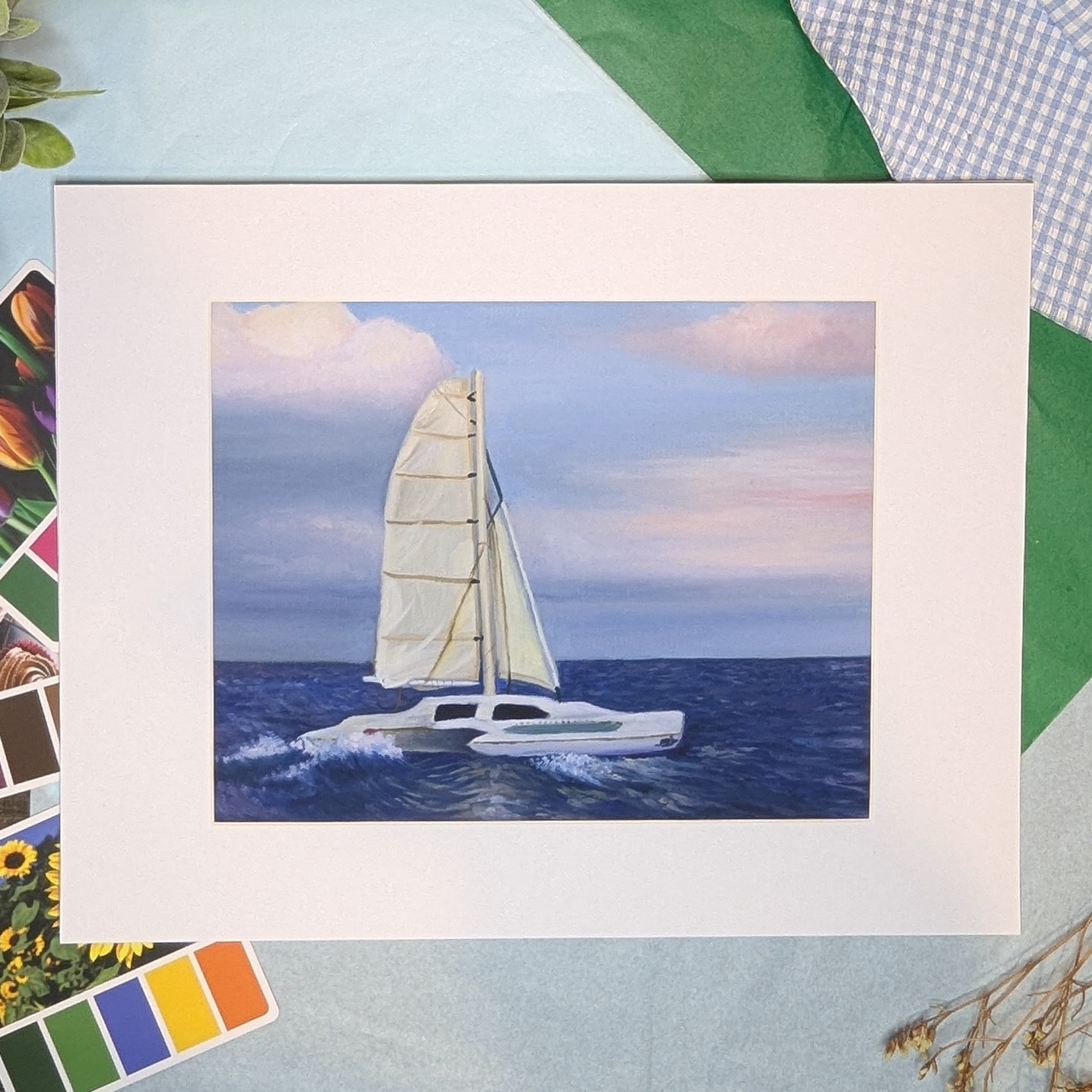 Framed artwork of a sailboat on water with a colorful border.