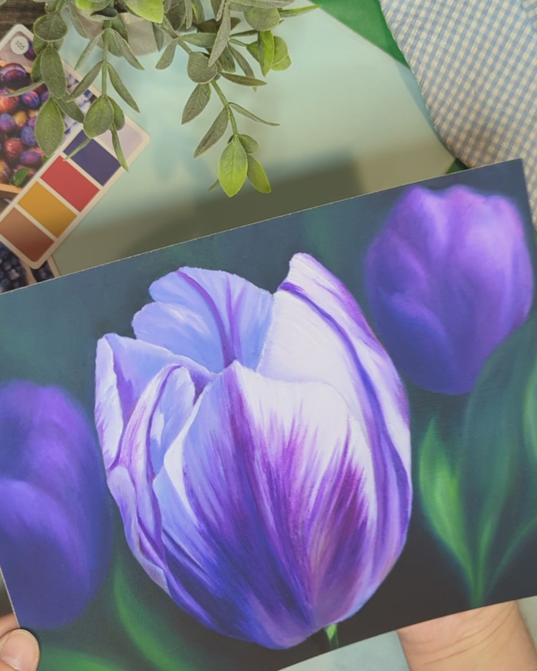 video of the artist holding a print of a painting of purple tulips