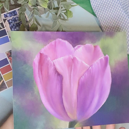 artist holding a print of an original painting of a tulip with a colorful background