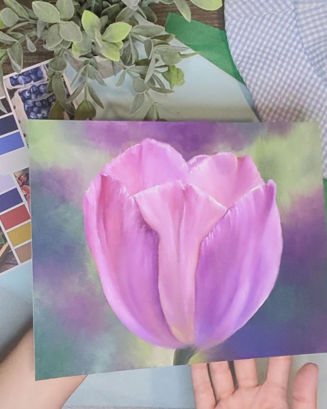 artist holding a print of an original painting of a tulip with a colorful background